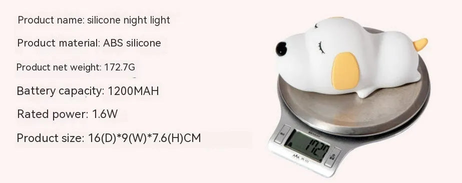 Soft silicone cartoon dog night light with USB cable on a bedside table.