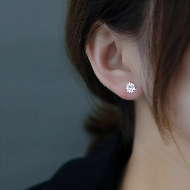 Silver snowflake ear stud earrings for women with zircon detail and copper base, geometric compact design.