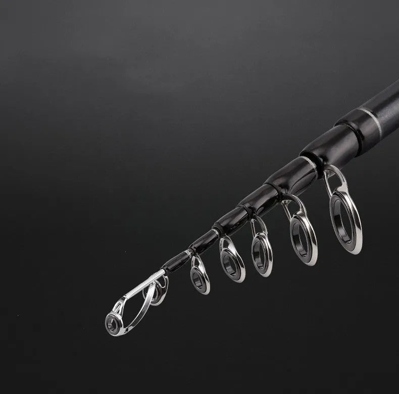 Telescopic carbon fishing rod extended on ground near water, straight handle 2.1m length visible