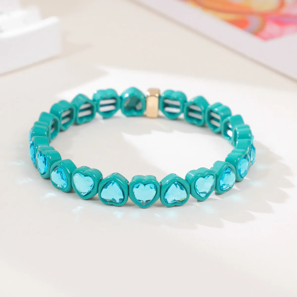 Colourful enamel finish alloy heart charm on a black stretch bracelet band.
