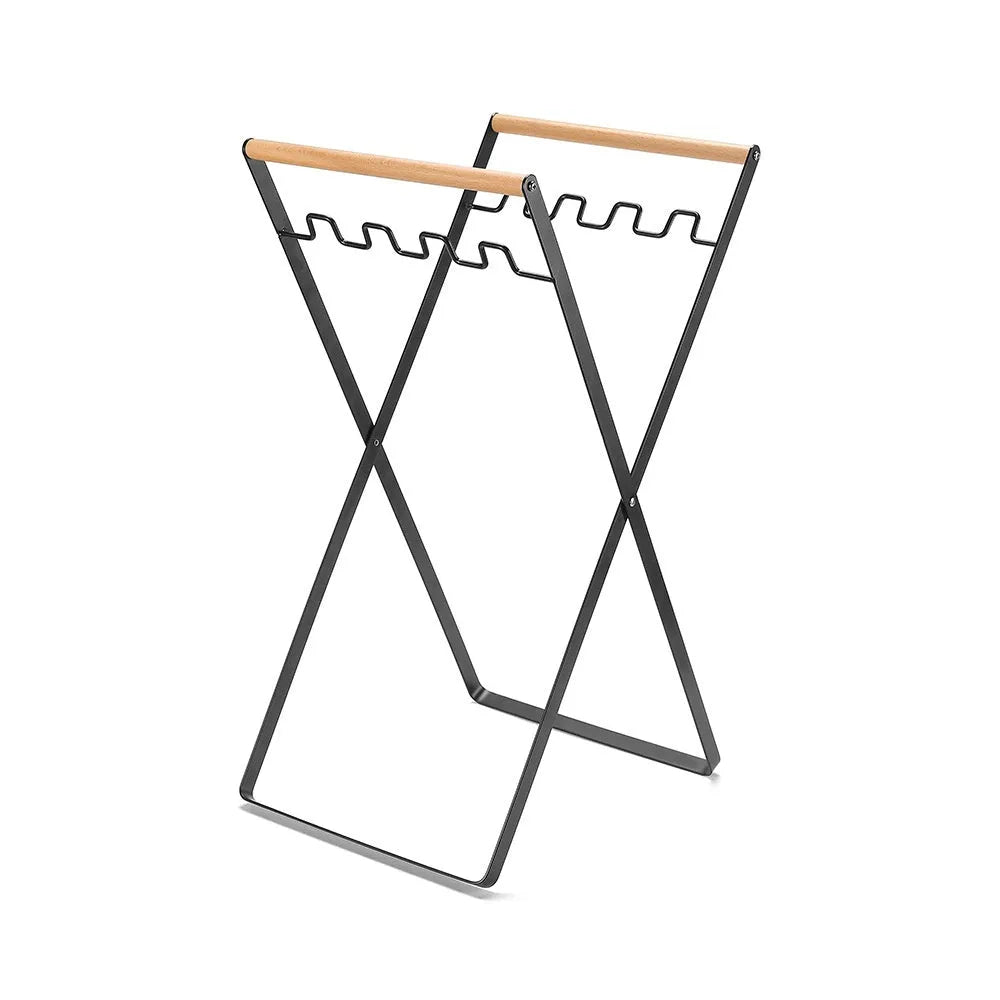 Foldable black wrought iron garbage storage hanger with a wooden handle, shown holding a bin bag.