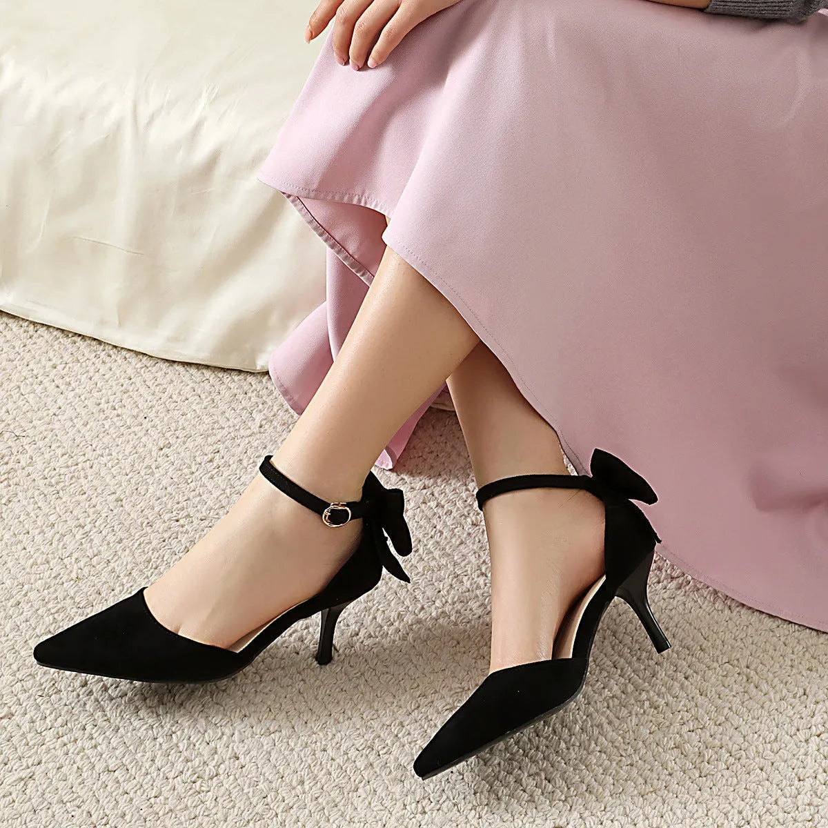 Black suede pointed-toe stiletto high heels with a bowknot detail and buckle fastening.