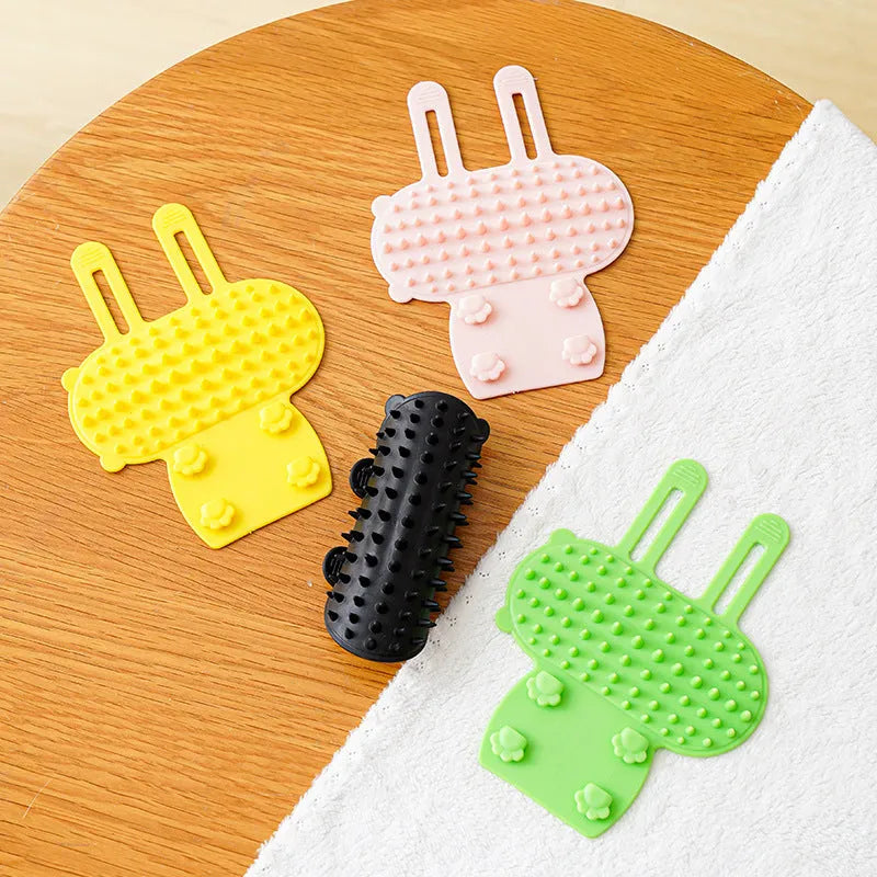 Silicone cat grooming massage comb with adjustable strap mounted on furniture leg
