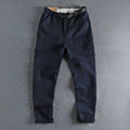 Men's khaki cotton work trousers with a buckle belt and three-dimensional cut on a hanger.