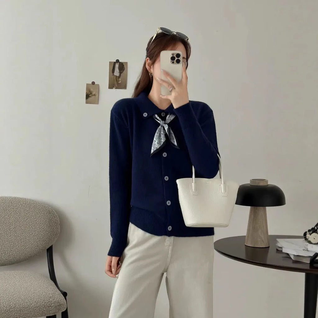 Milky white acrylic cardigan sweater with lapel collar and scarf trim detail, long sleeves.
