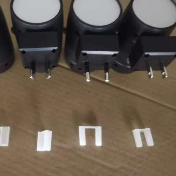 Small white plug-in night lamp with a rotatable head and adjustable brightness control on a grey background.