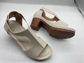Women's beige peep toe wedge sandals with ankle buckle, shown on a foot.