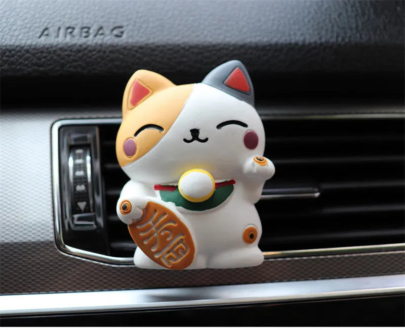 Black and white cat resin aromatherapy clip attached to a car air conditioning vent.