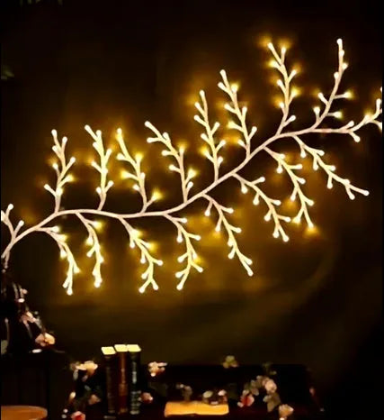 Flexible willow vine Christmas garland with warm white LED lights bent into a decorative shape on a wall.