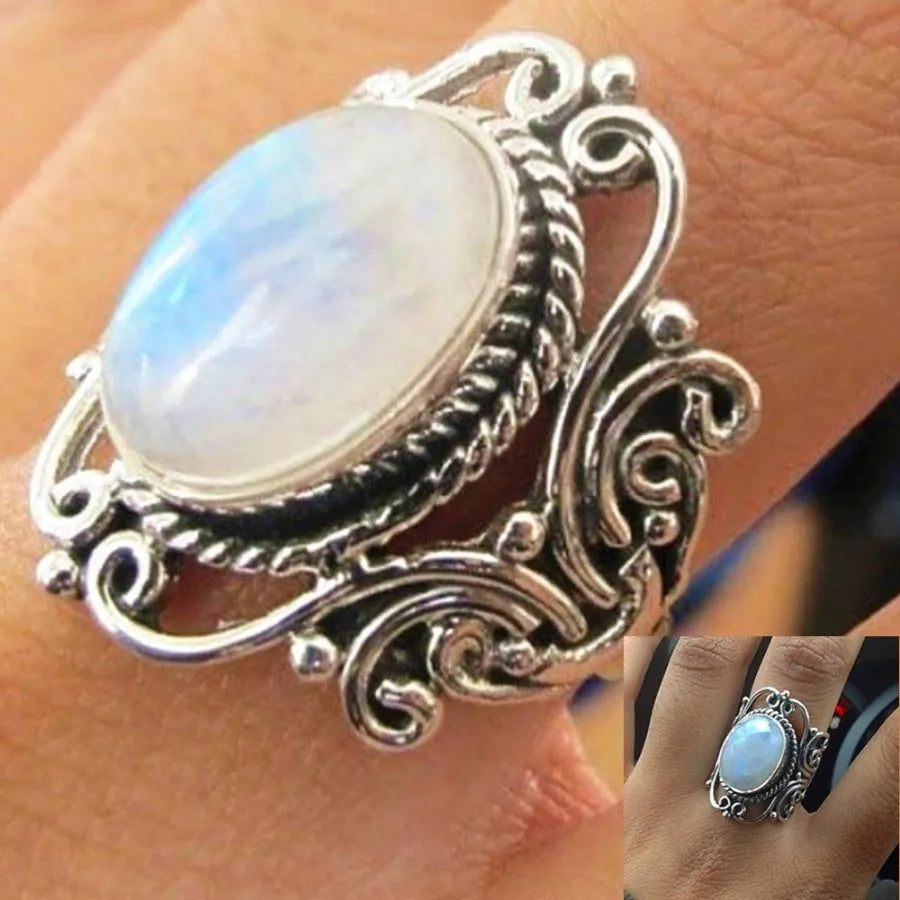Vintage alloy ring with flower-shaped artificial moonstone gemstone on a neutral background showing side view