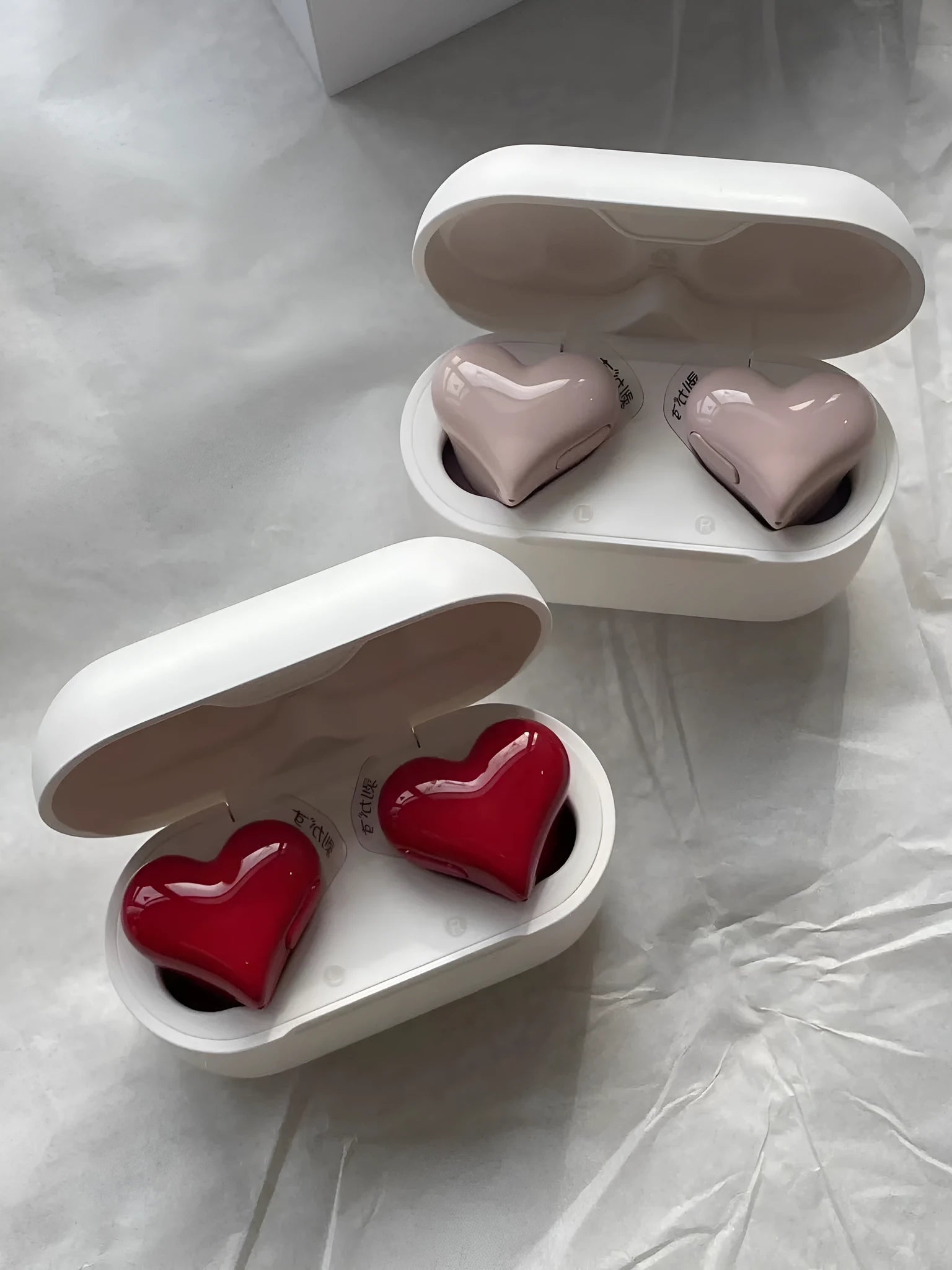 Heart-shaped wireless Bluetooth earphones in red and pink colours with charging cable