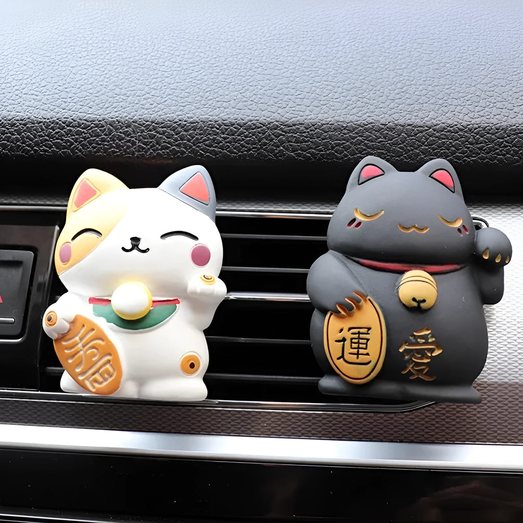 Black and white cat resin aromatherapy clip attached to a car air conditioning vent.