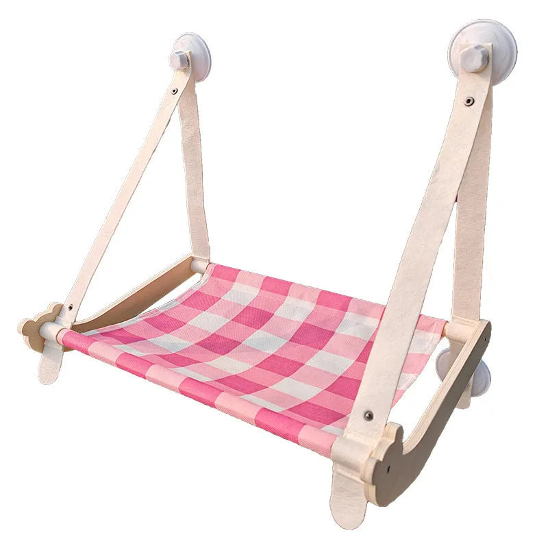 Pink foldable wooden cat window bed with suction cups attached to a glass window