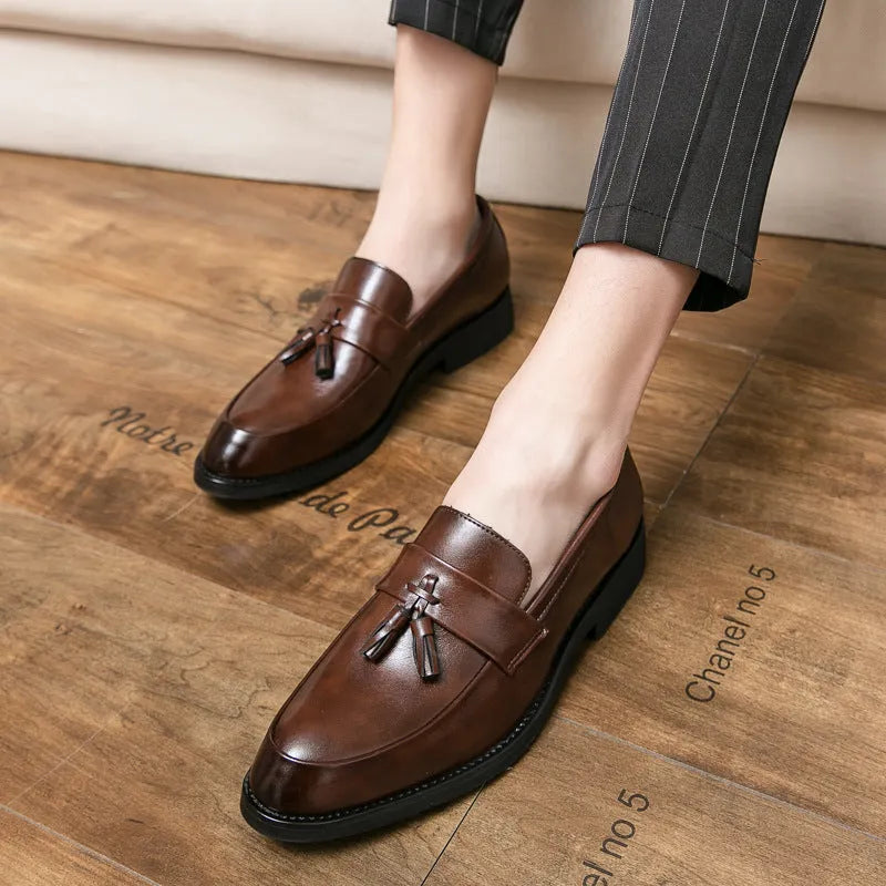Men's black and brown slip-on business casual shoes with tassel detail and rubber sole.