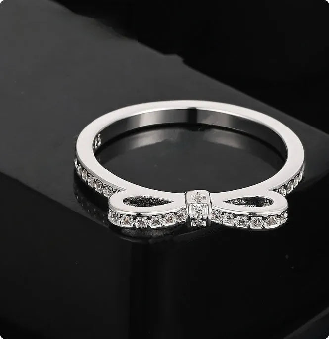 Silver-colour bow ring with zircon crystal details on a white background.