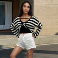 Woman wearing a striped long-sleeved sweater with an exposed navel, showcasing front and back wearable design in mercerised cotton.