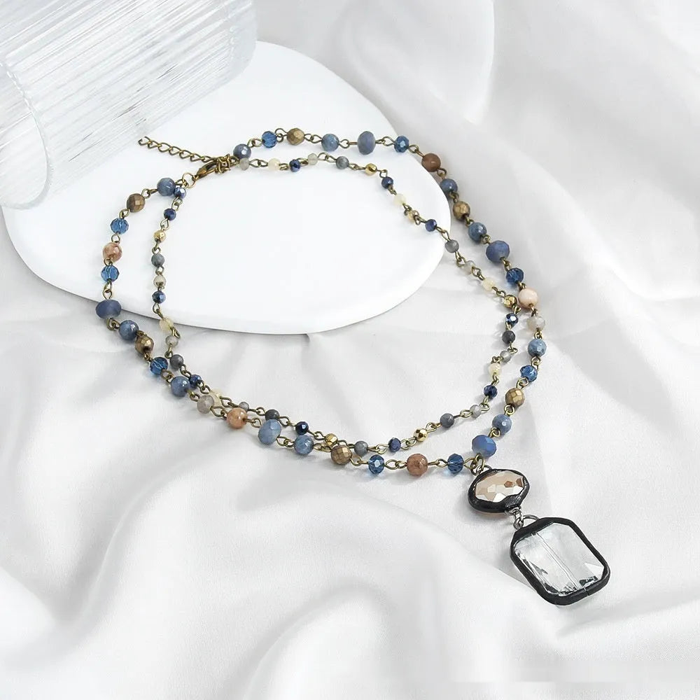 Beige and blue two-layer tribal style necklace with glass pendant and stone accents on adjustable chain