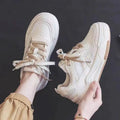 Women's beige and pink low-top lace-up sneakers with a rubber sole on a white background.