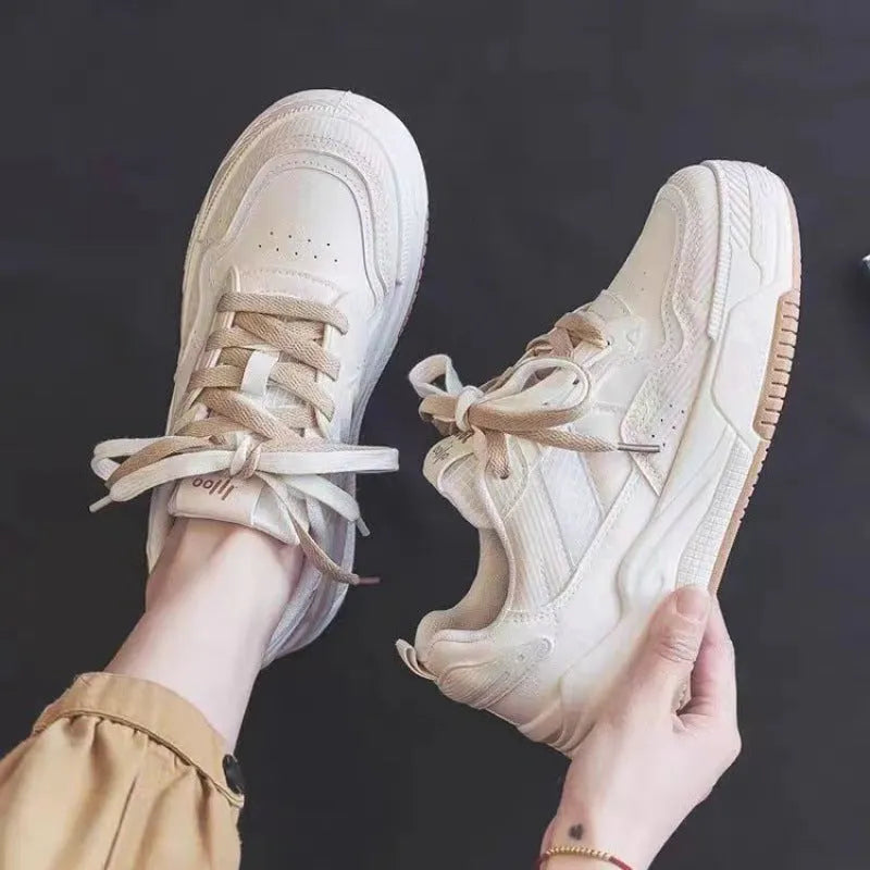 Women's beige and pink low-top lace-up sneakers with a rubber sole on a white background.