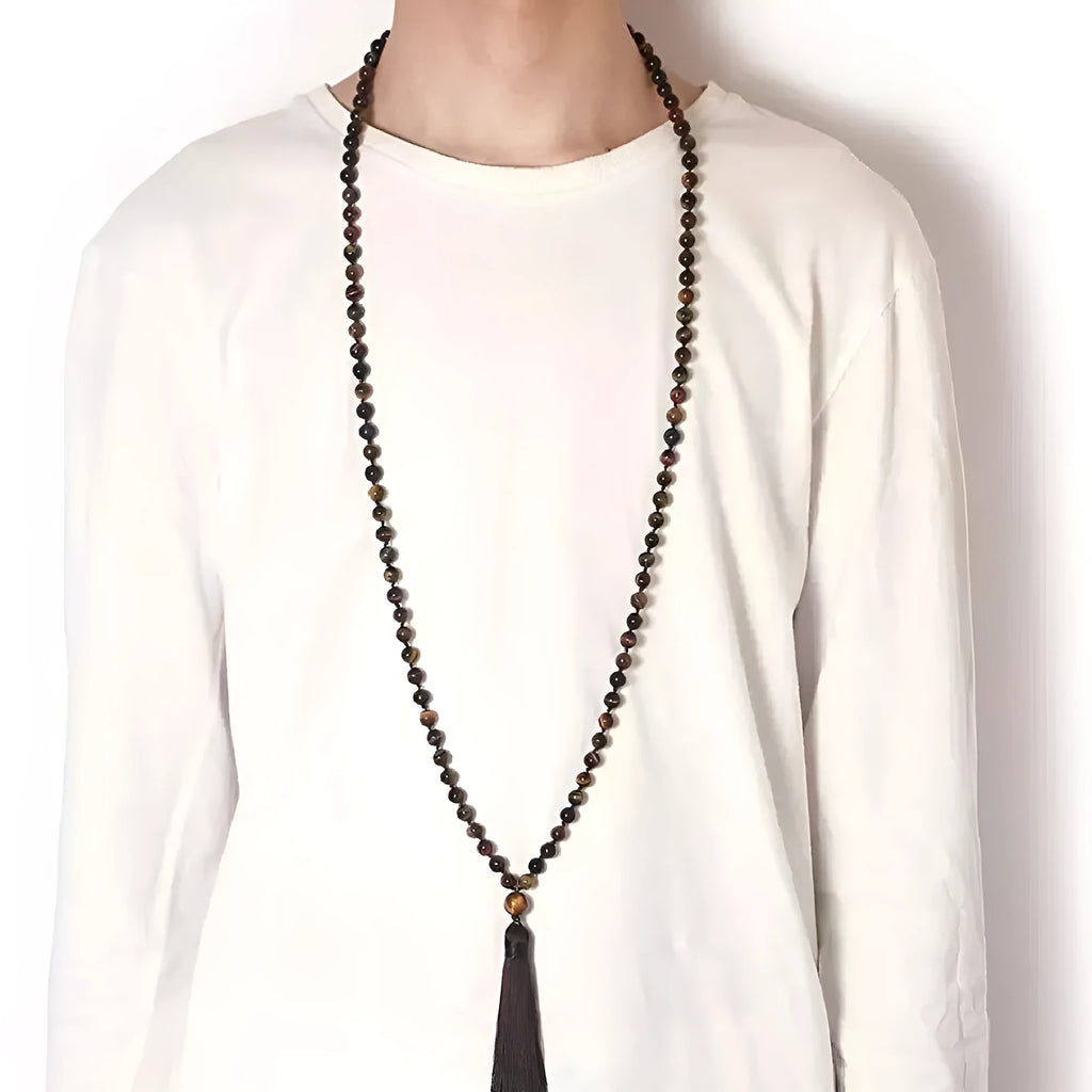 Long beaded agate and amethyst tassel necklace with geometric pendant on a neutral background.