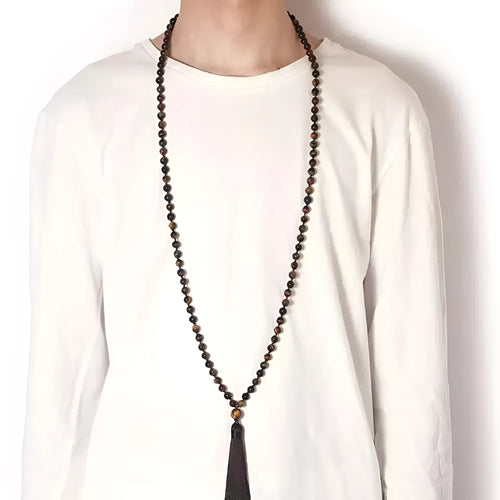 Long beaded agate and amethyst tassel necklace with geometric pendant on a neutral background.