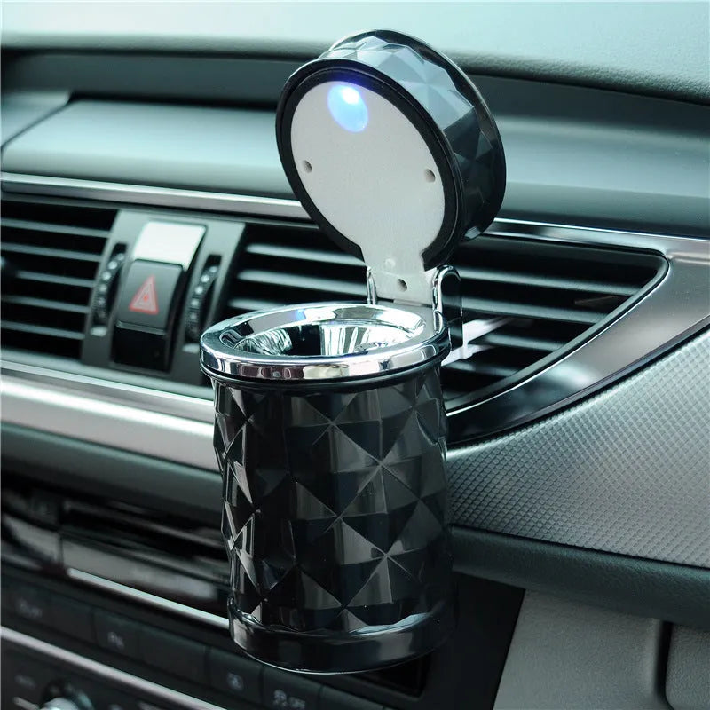 Black car ashtray made of ABS plastic hanging from a car air outlet vent.