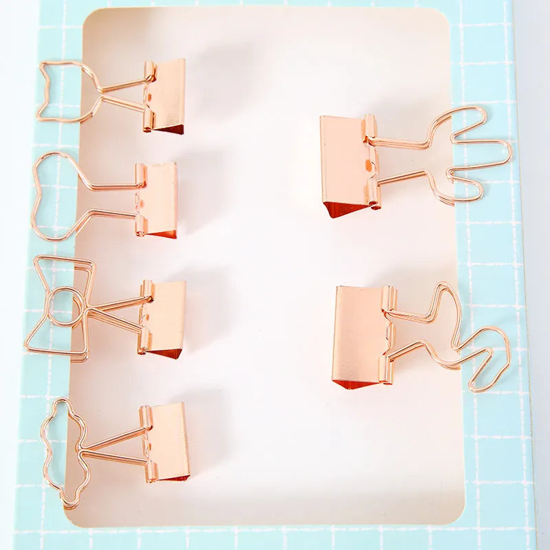 Gold metal decorative paper clip in a bow shape with a long tail design.