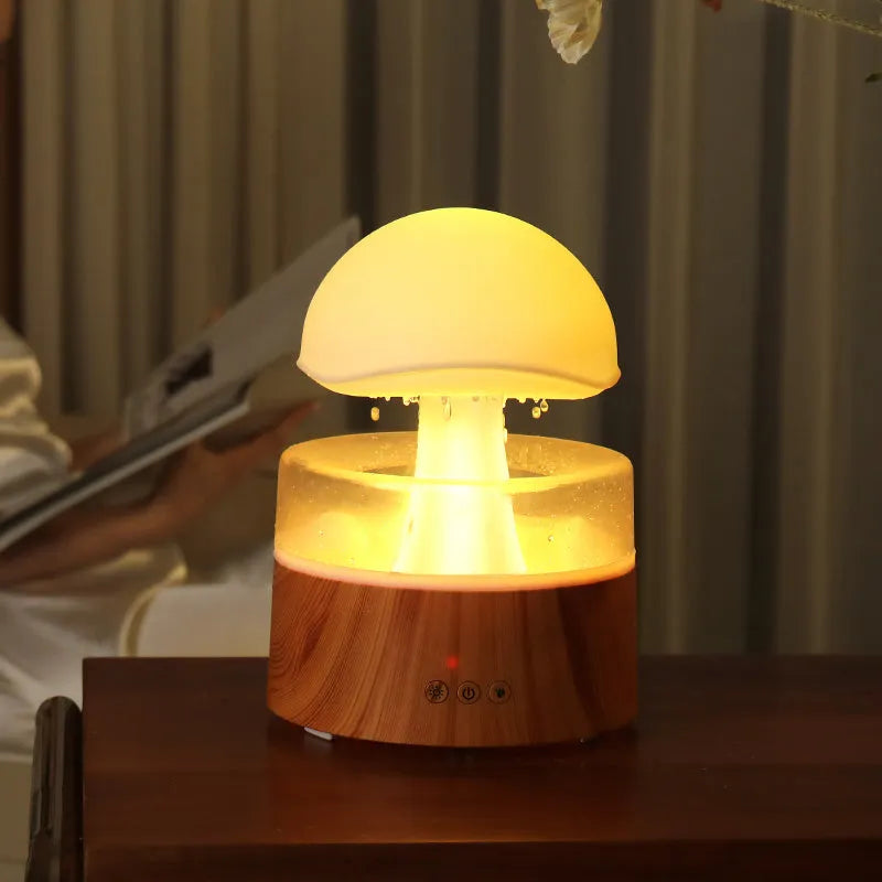 White cloud-shaped humidifier with falling raindrop mist and multi-colour night light on wooden table