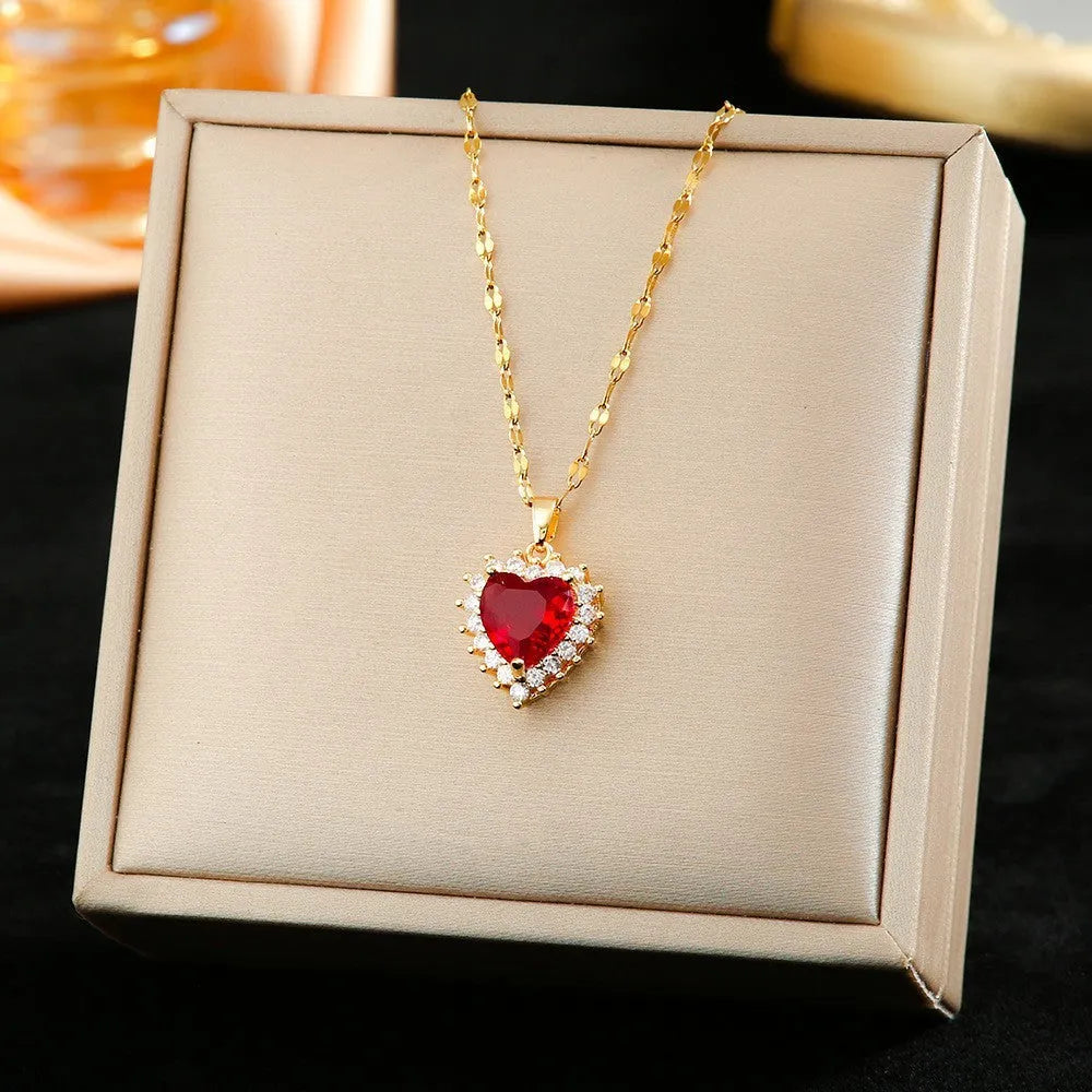 Gold red titanium steel necklace with heart pendant and gemstone inlay, part of a matching jewellery suit.