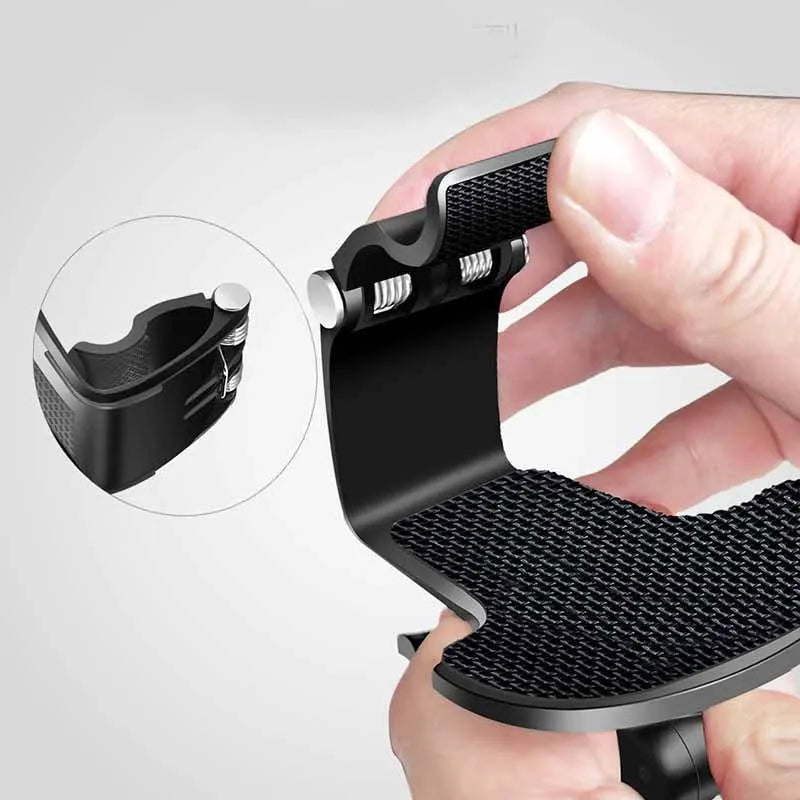Black multifunctional car phone holder clipped onto a car sun visor, holding a smartphone.