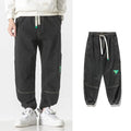 Men's loose-fit tapered cotton trousers in grey shown on a hanger.