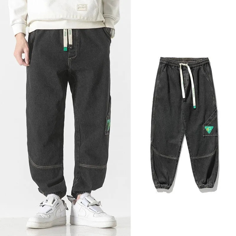 Men's loose-fit tapered cotton trousers in grey shown on a hanger.