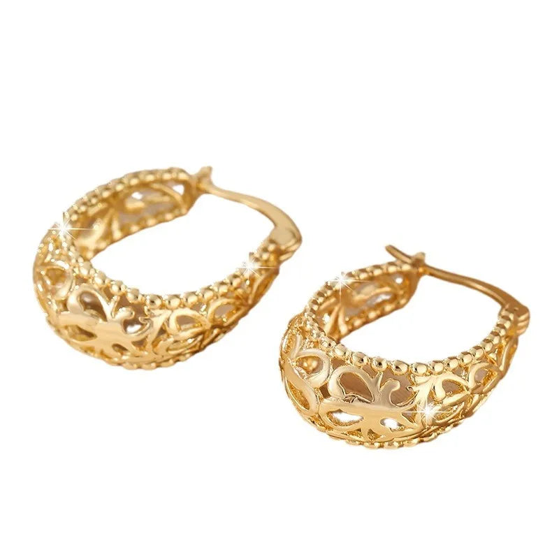 Gold copper geometric hollowed-out large earrings with round shape on neutral background