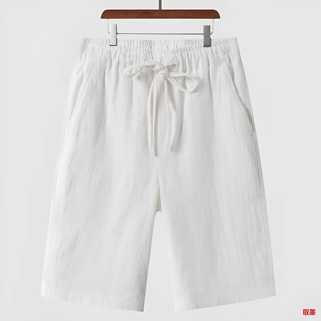 Man wearing beige loose-fit linen cropped shorts with an elastic mid waist.