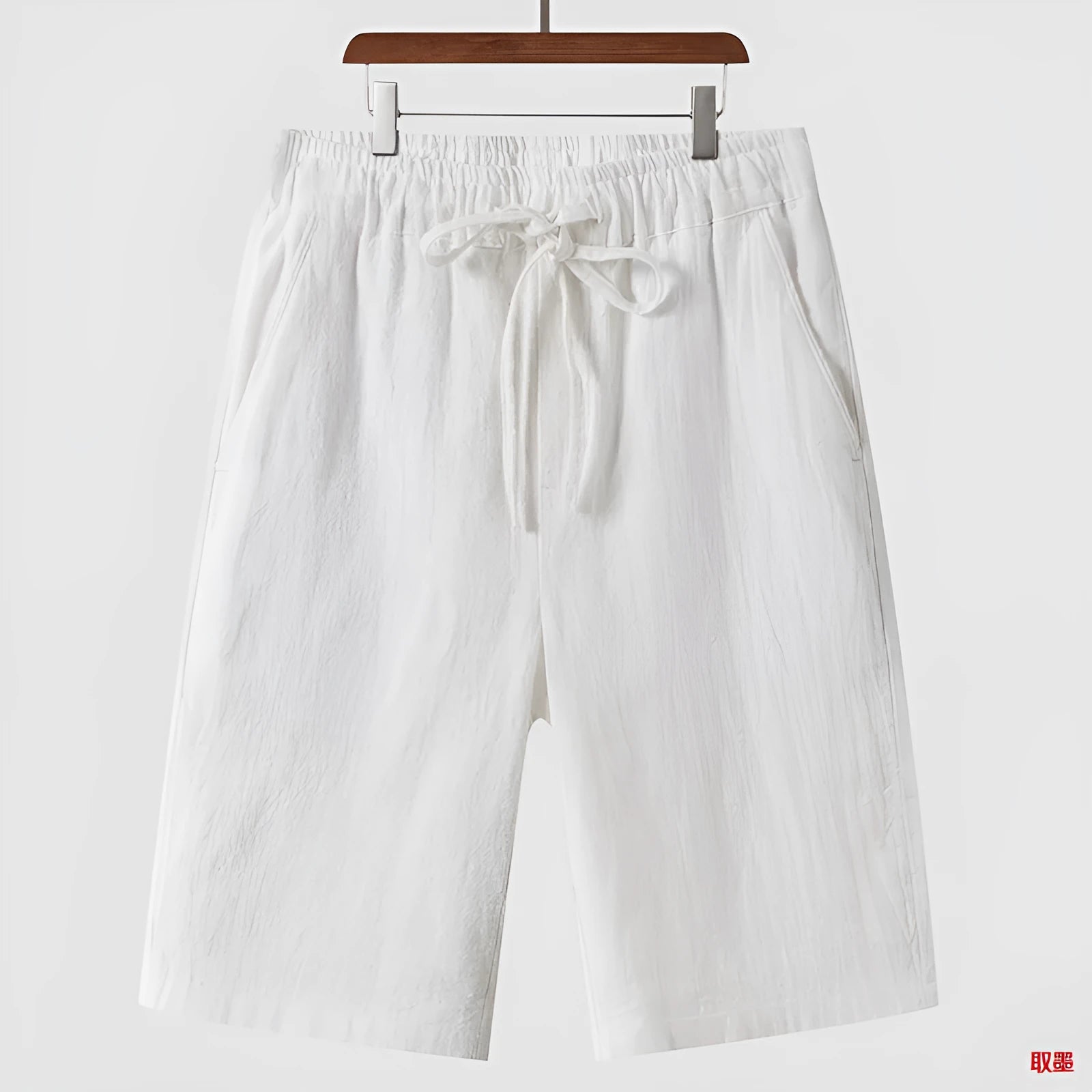 Man wearing beige loose-fit linen cropped shorts with an elastic mid waist.
