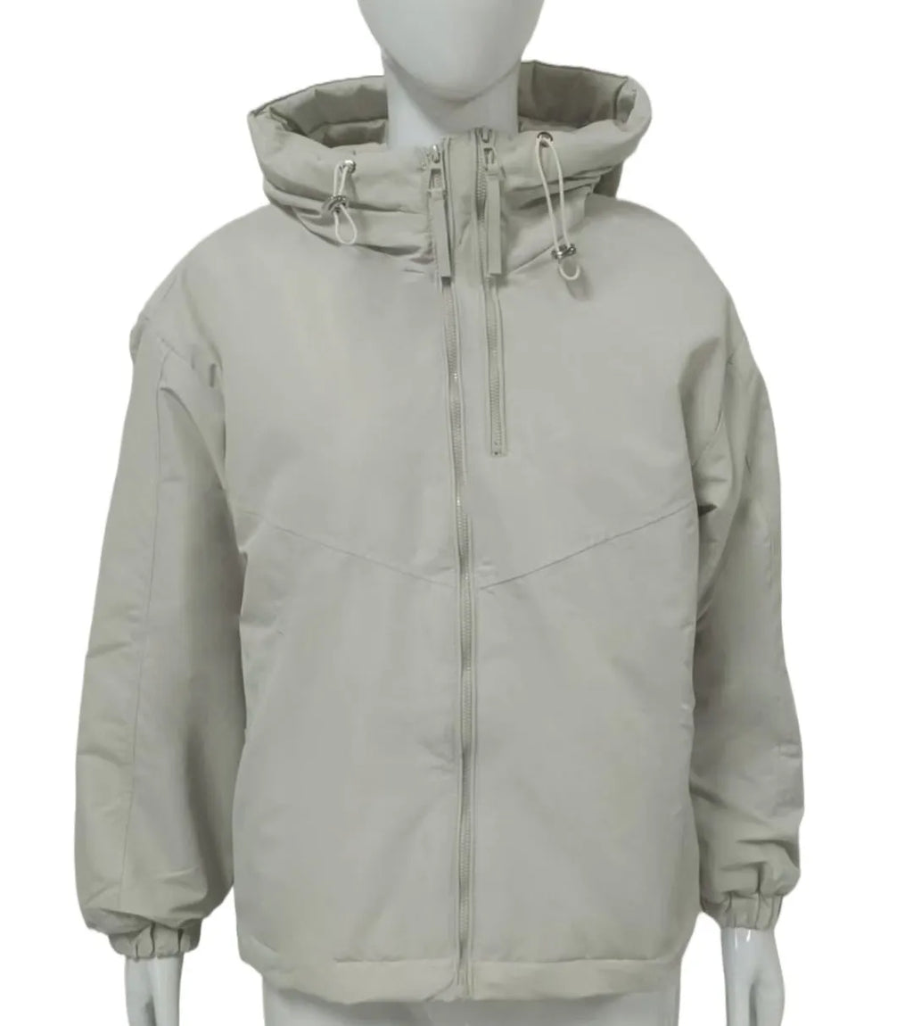 A woman wearing a loose-fitting grey hooded shell jacket with long sleeves, showing the front zip closure.