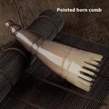 Black horn head massage comb with wide teeth and a pointed tip on a white background