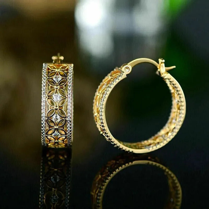 A pair of gold-coloured geometric butterfly earrings with floral details and horse eye styling on a white background.