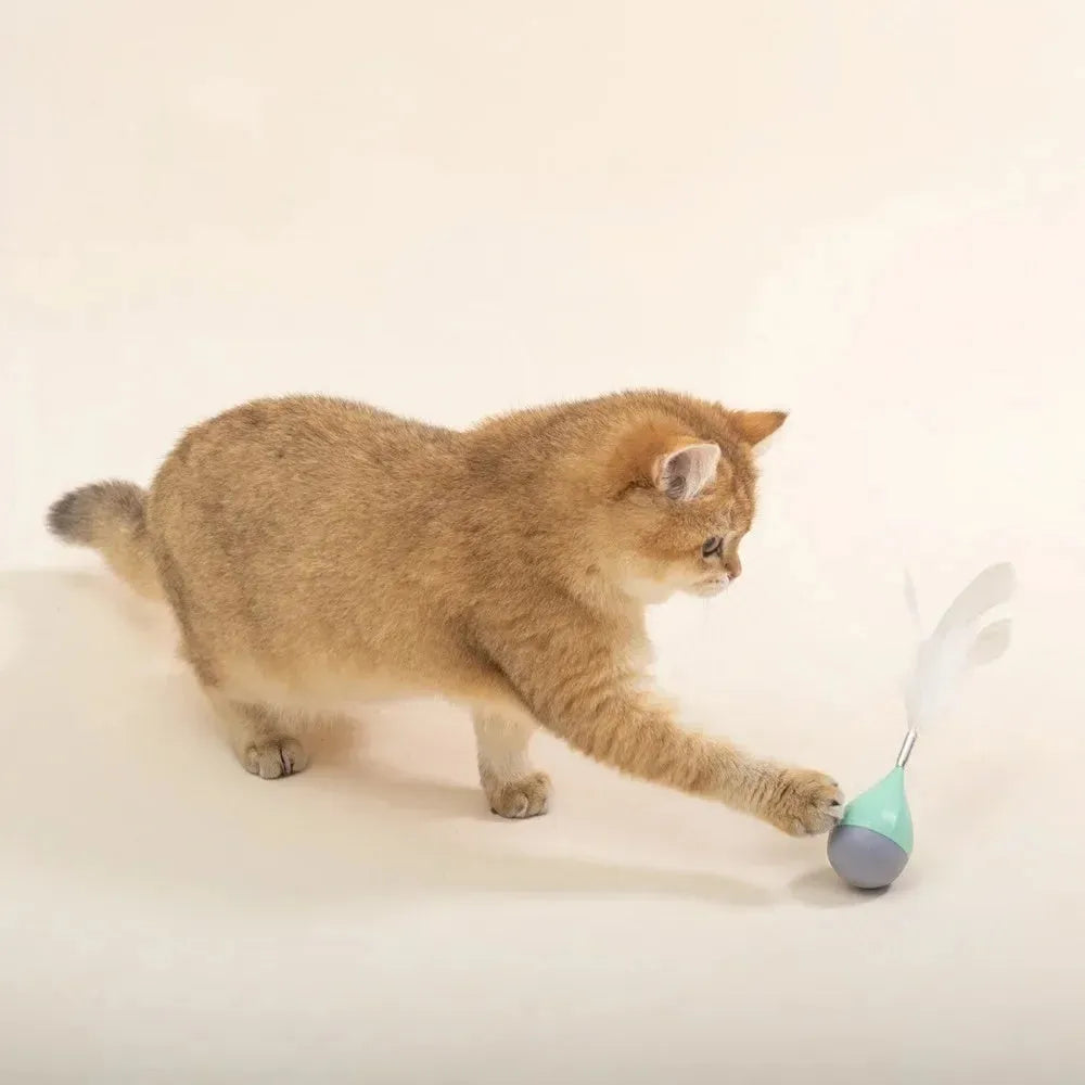 Green feather tumbler cat toy with goose feathers and aluminium alloy components on wooden floor
