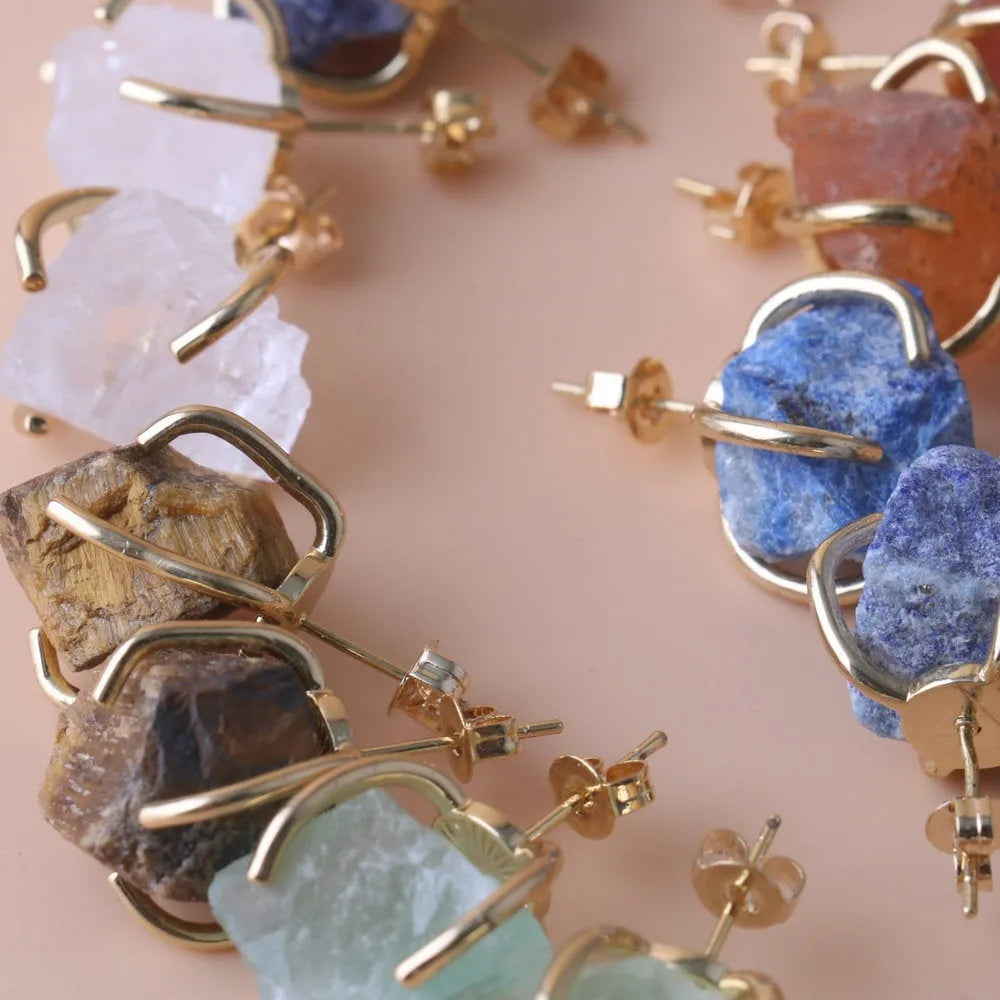 Rough stone crystal earrings with gold plated four claws on a black background