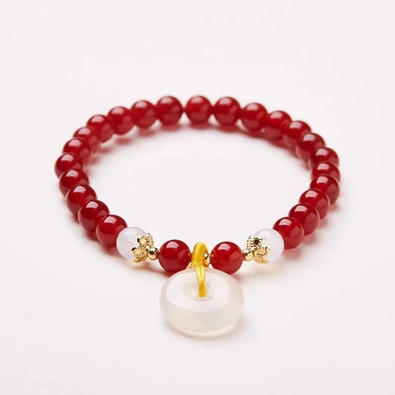 Handmade natural jade and red agate bracelet with silver safety buckle on wooden background