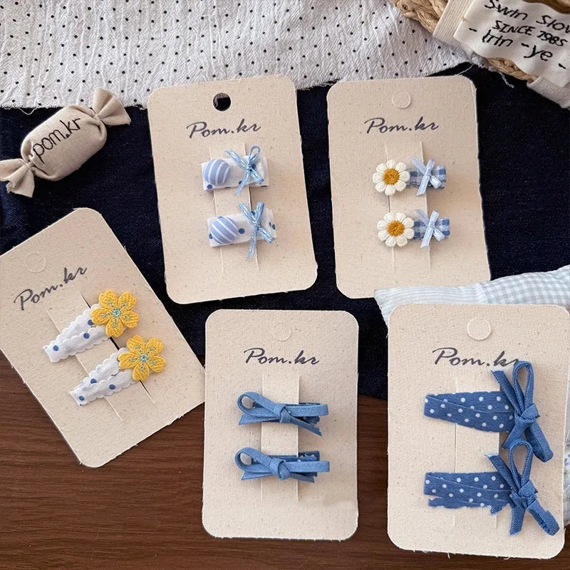 Children's denim handmade flower polka dot bow barrettes with triangle and duckbill clips on a light background