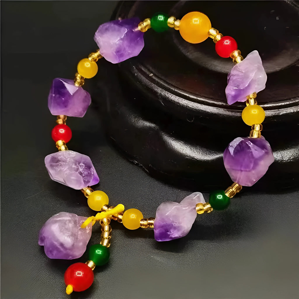Women's natural shaped violet amethyst bead bracelet with a fu character pendant on a white background.
