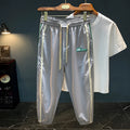 Men's black cotton harem-style casual trousers with a tapered leg on a grey background.