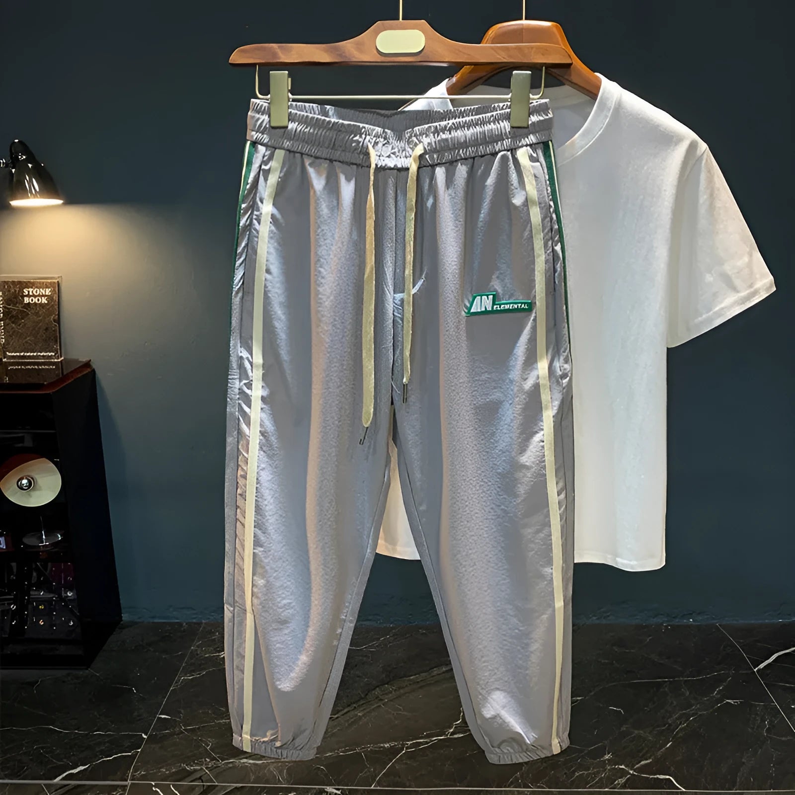 Men's black cotton harem-style casual trousers with a tapered leg on a grey background.