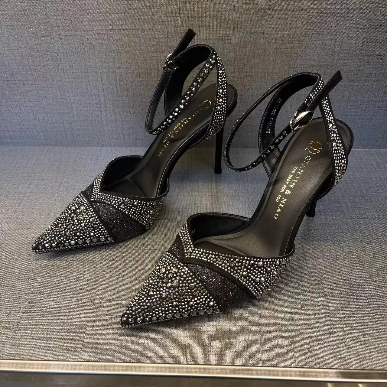 Women's black hollow high heel with stiletto heel, pointed toe, and red sole on a light background.