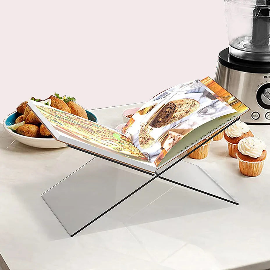 Clear acrylic X-shaped book reading rack displaying a book on a desktop