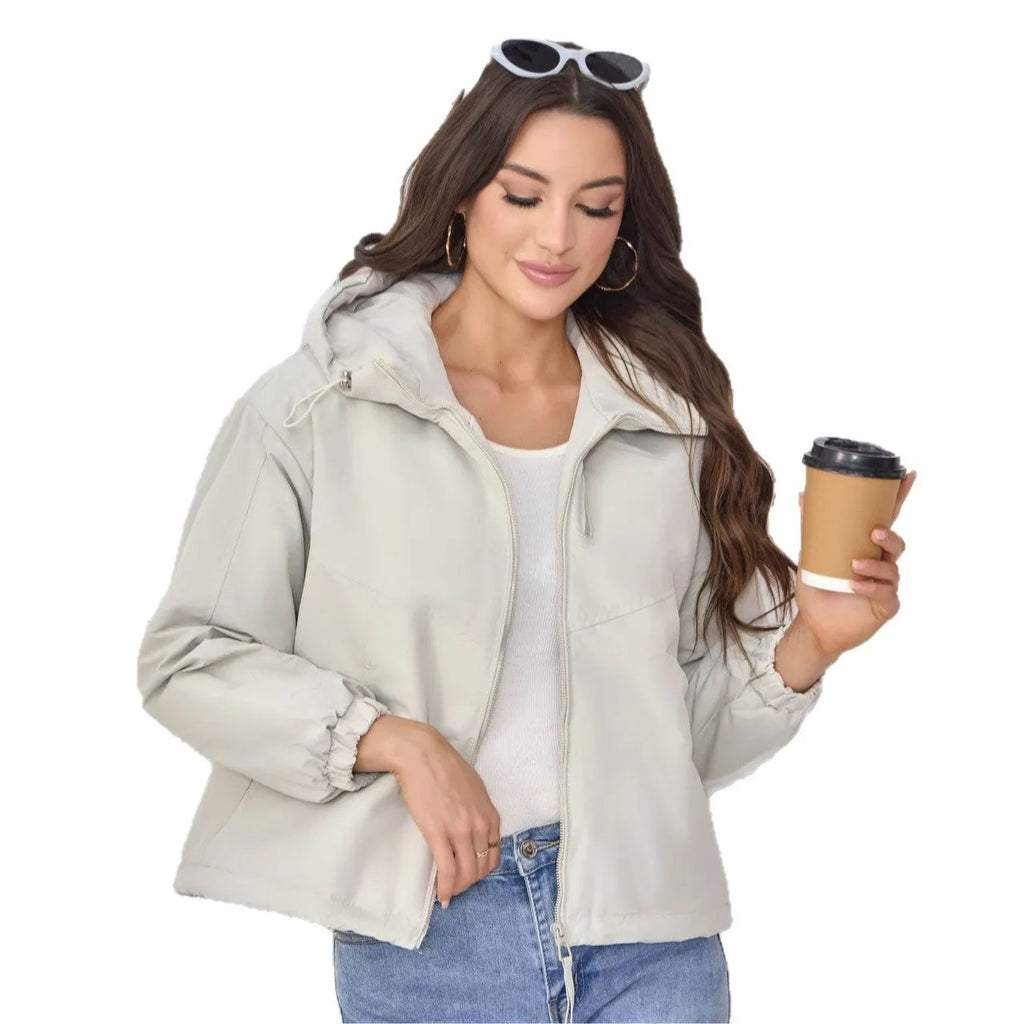A woman wearing a loose-fitting grey hooded shell jacket with long sleeves, showing the front zip closure.