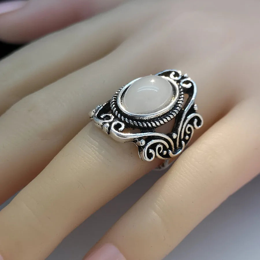 Vintage alloy ring with flower-shaped artificial moonstone gemstone on a neutral background showing side view