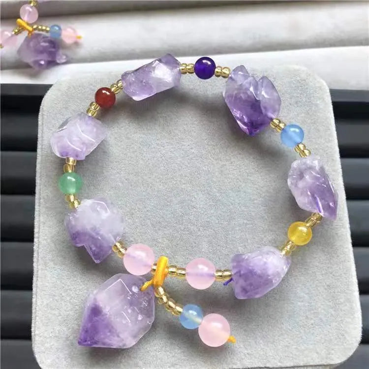 Women's natural shaped violet amethyst bead bracelet with a fu character pendant on a white background.